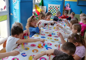 Dzieci napełniają probówki kolorowymi barwnikami